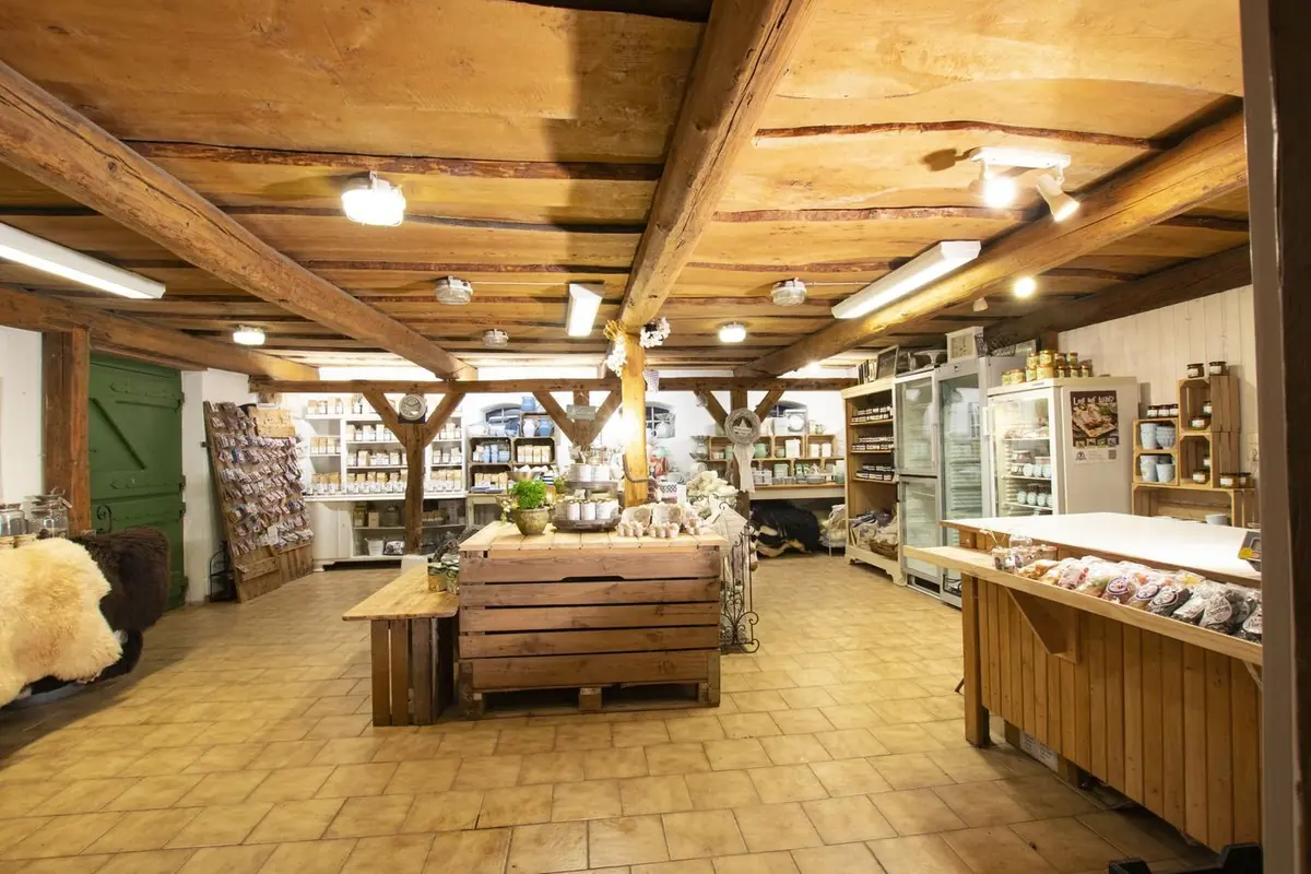 Innenansicht des Landladens mit alten Holzbalken, Regalen voller Produkte und der Frischetheke